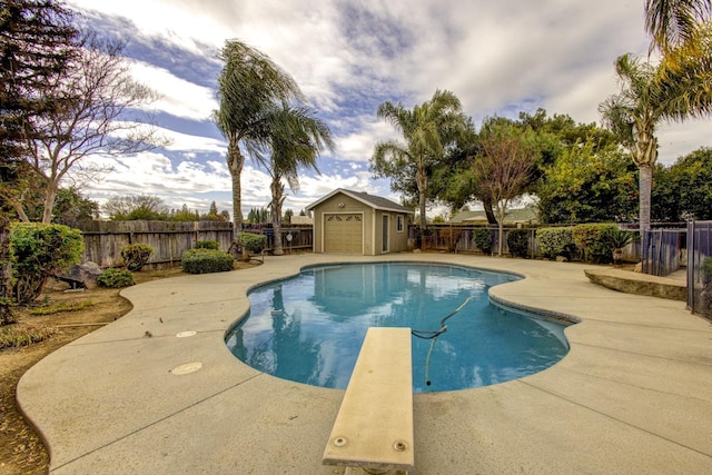 view of swimming pool featuring an outbuilding, a diving board, and a patio area