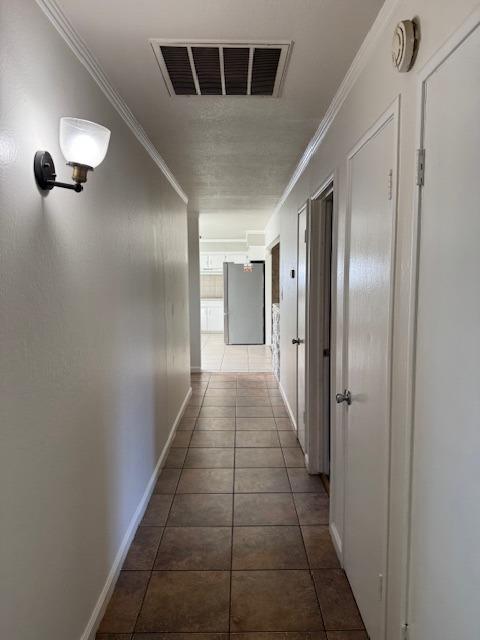 hallway with dark tile patterned floors and crown molding