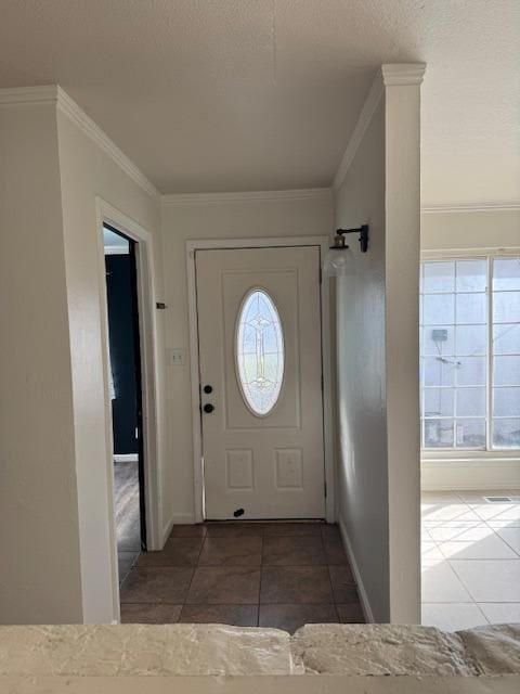 entrance foyer with ornamental molding, dark tile patterned flooring, and a wealth of natural light