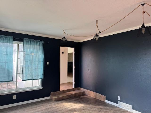 unfurnished room featuring hardwood / wood-style flooring, crown molding, and a wealth of natural light