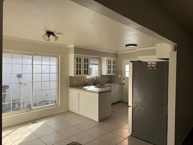 kitchen with white cabinetry, light tile patterned floors, stainless steel refrigerator, and dishwasher