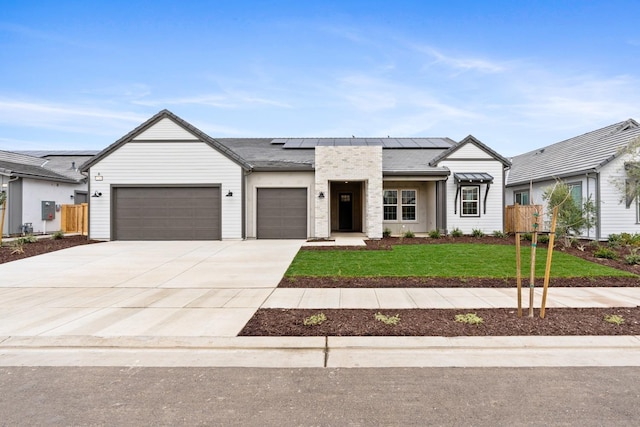 view of front of house with a garage, a front lawn, and solar panels