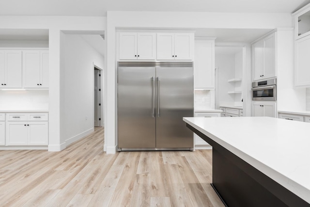 kitchen featuring white cabinetry, tasteful backsplash, stainless steel appliances, and light wood-type flooring