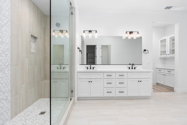 bathroom featuring vanity, wood-type flooring, and tiled shower