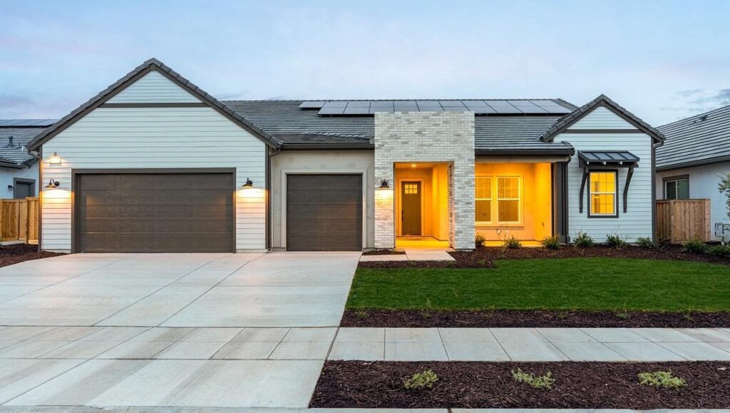 view of front of property with a garage, a lawn, and solar panels