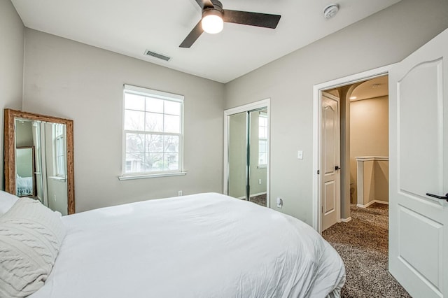 bedroom with ceiling fan, dark carpet, and a closet