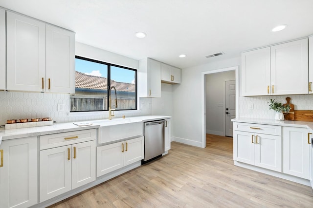 kitchen with sink, white cabinets, decorative backsplash, stainless steel dishwasher, and light wood-type flooring