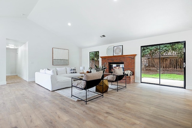 living room featuring a fireplace, high vaulted ceiling, and light hardwood / wood-style flooring