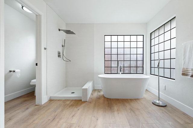 bathroom with hardwood / wood-style floors, toilet, and separate shower and tub