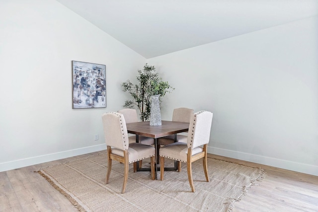 dining area featuring vaulted ceiling and light hardwood / wood-style floors