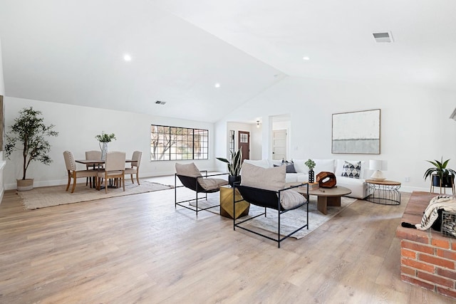 living room featuring high vaulted ceiling and light hardwood / wood-style floors