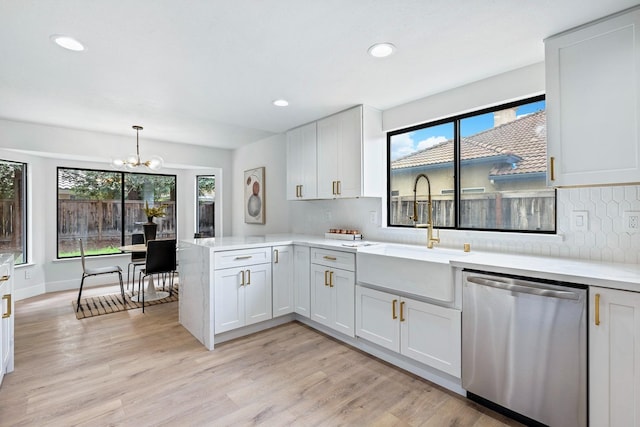 kitchen with pendant lighting, sink, white cabinets, stainless steel dishwasher, and kitchen peninsula