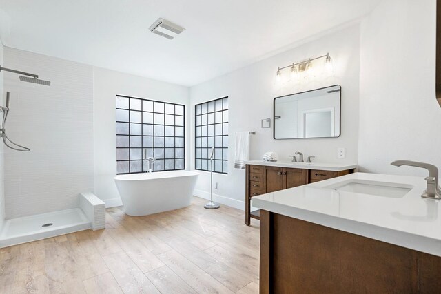 5017 W Locust Ave, Fresno, CA 93722 - bathroom with vanity, tiled shower, a soaking tub, and wood finished floors