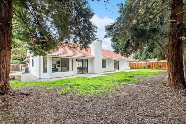 rear view of property with a yard, a patio, and central air condition unit