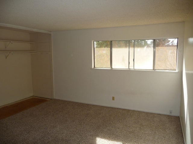 unfurnished bedroom with carpet floors, a textured ceiling, and a closet