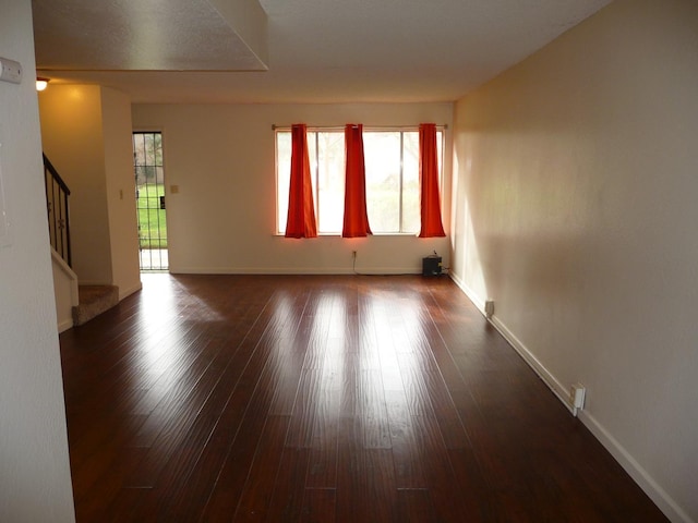 empty room with dark hardwood / wood-style floors and a wealth of natural light