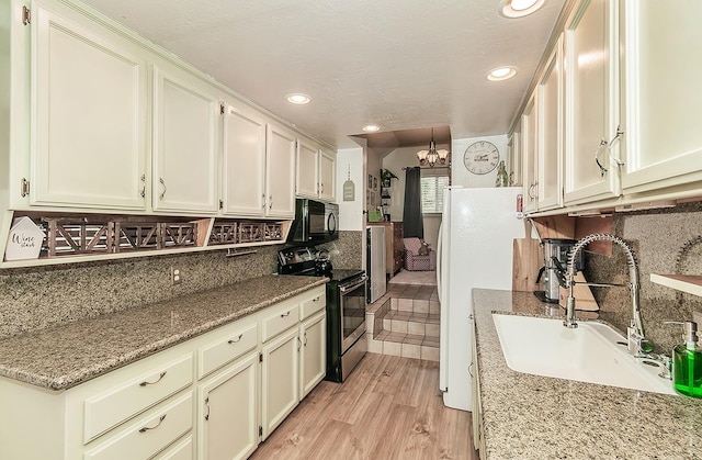 kitchen with sink, stainless steel range with electric stovetop, light hardwood / wood-style floors, light stone counters, and an inviting chandelier