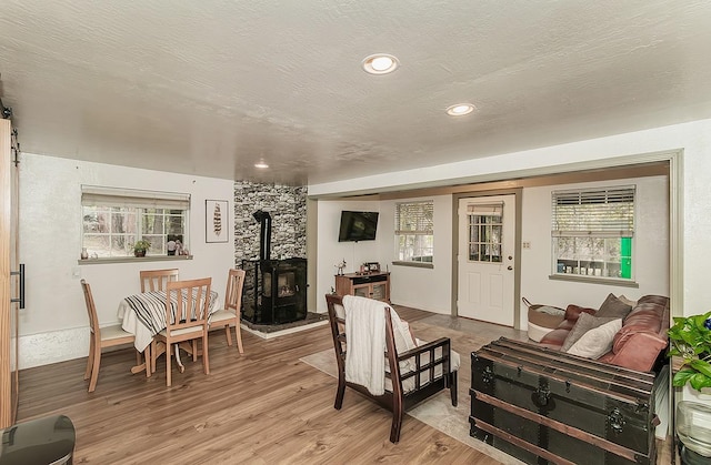 living room featuring light wood-type flooring, a textured ceiling, and a wood stove