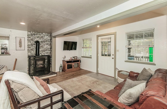 living room featuring wood-type flooring, a wood stove, and a textured ceiling