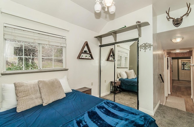 carpeted bedroom featuring an inviting chandelier, vaulted ceiling, and a closet