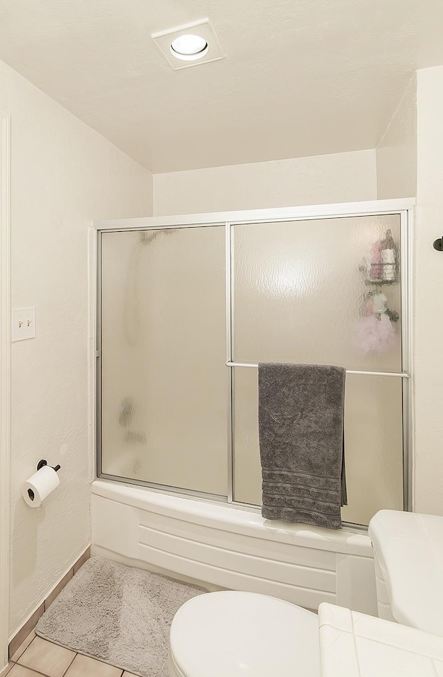 bathroom with enclosed tub / shower combo, tile patterned floors, and toilet