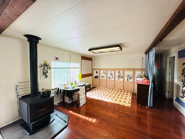 interior space featuring a wood stove, dark wood-type flooring, and a textured ceiling