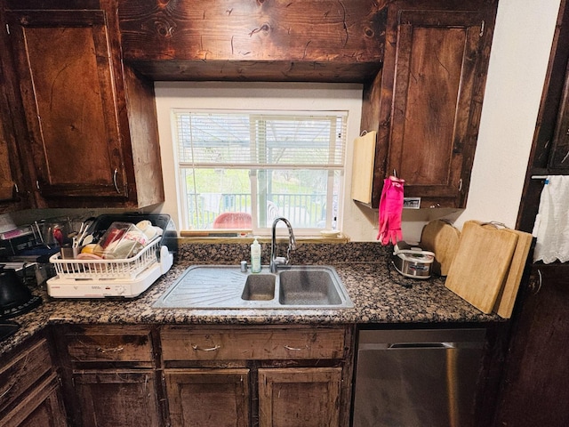 kitchen with dark brown cabinetry, sink, stainless steel dishwasher, and dark stone countertops