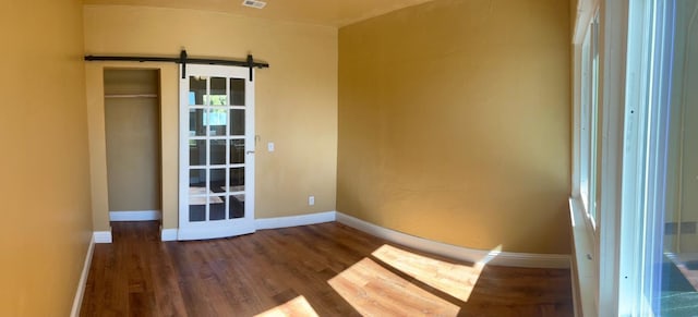 empty room featuring dark wood-type flooring and a barn door