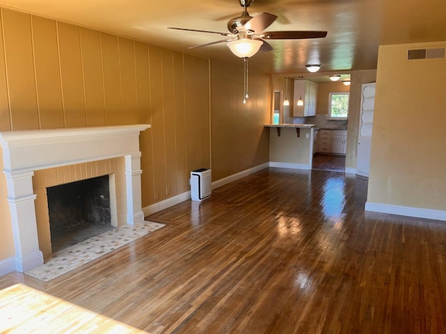 unfurnished living room with dark wood-type flooring, ceiling fan, and a tile fireplace