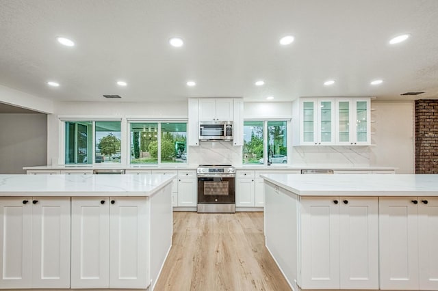 kitchen featuring light stone counters, light hardwood / wood-style flooring, white cabinets, and appliances with stainless steel finishes