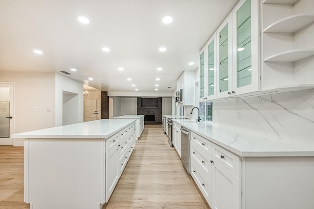 kitchen featuring light stone countertops, white cabinets, and a spacious island