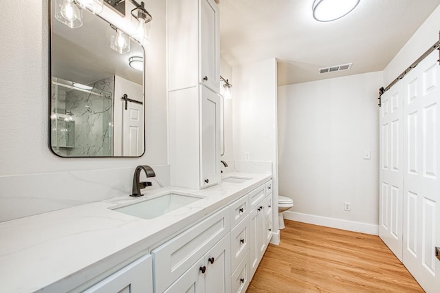 bathroom featuring vanity, hardwood / wood-style floors, walk in shower, and toilet