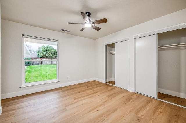 unfurnished bedroom featuring ceiling fan, two closets, and light wood-type flooring