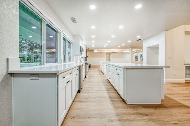 kitchen with light hardwood / wood-style flooring, white cabinets, and a spacious island