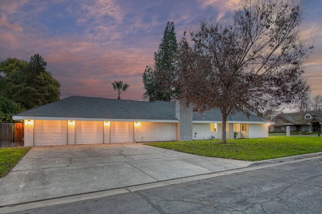 view of front of home with a garage and a lawn