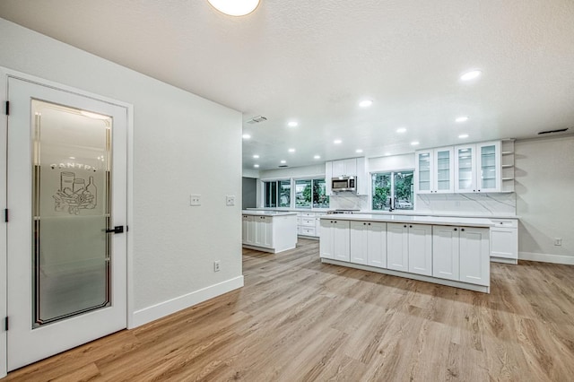 kitchen featuring white cabinetry, backsplash, light hardwood / wood-style floors, and a kitchen island