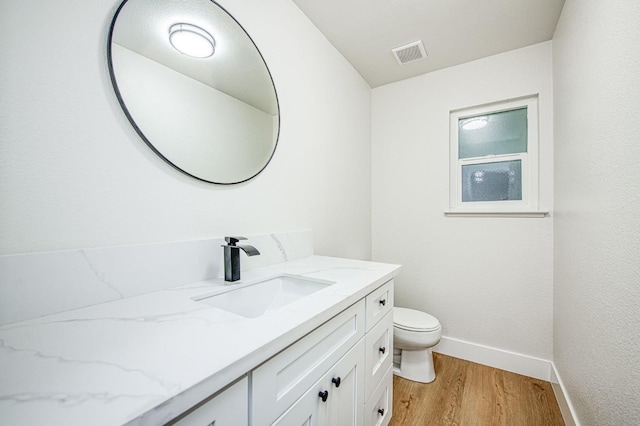 bathroom with wood-type flooring, vanity, and toilet