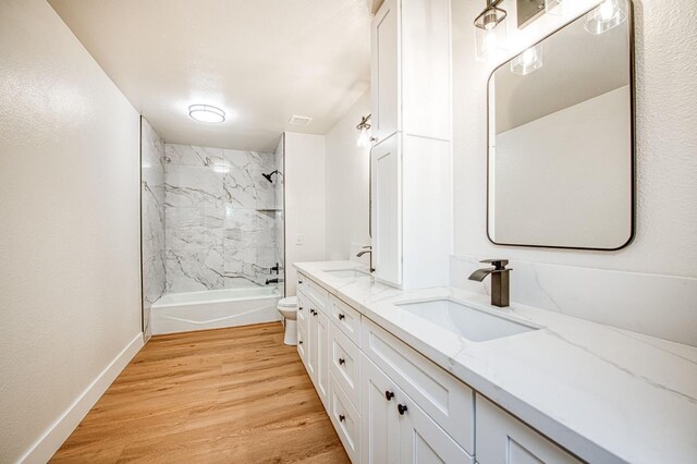 full bathroom featuring hardwood / wood-style flooring, tiled shower / bath, vanity, and toilet