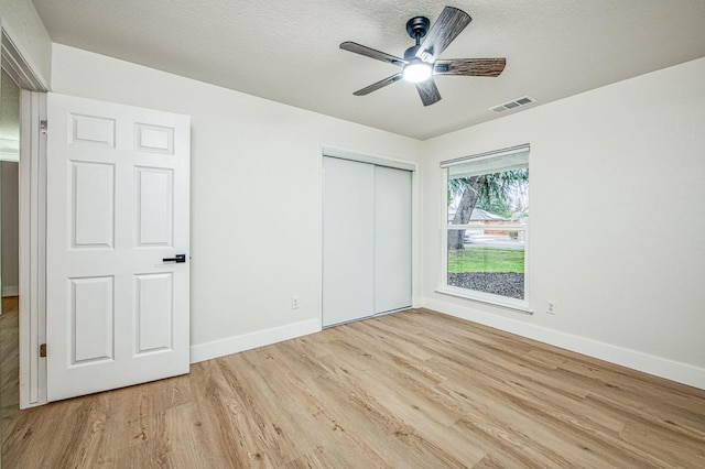 unfurnished bedroom with ceiling fan, a closet, a textured ceiling, and light wood-type flooring