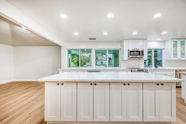 kitchen with light stone counters, stainless steel appliances, white cabinets, and a kitchen island