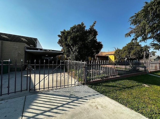 view of gate with a carport and a lawn