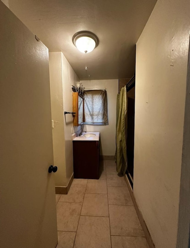 bathroom with tile patterned flooring, vanity, and walk in shower