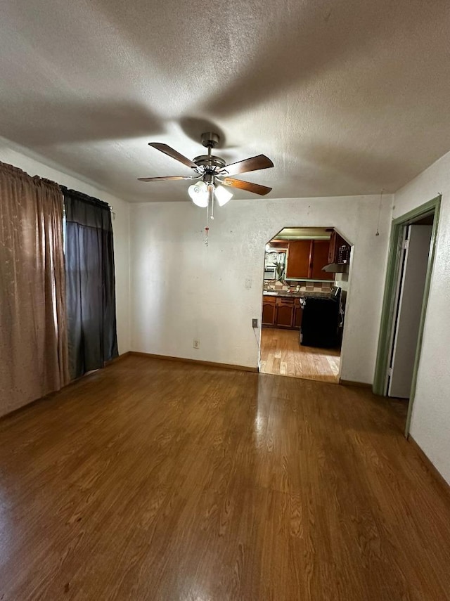 unfurnished living room featuring ceiling fan, light hardwood / wood-style flooring, and a textured ceiling