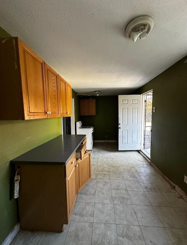 kitchen with washer and clothes dryer, a textured ceiling, and light tile patterned floors