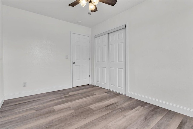 unfurnished bedroom with ceiling fan, wood-type flooring, and a closet