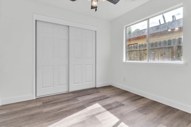 unfurnished bedroom with ceiling fan, light wood-type flooring, and a closet