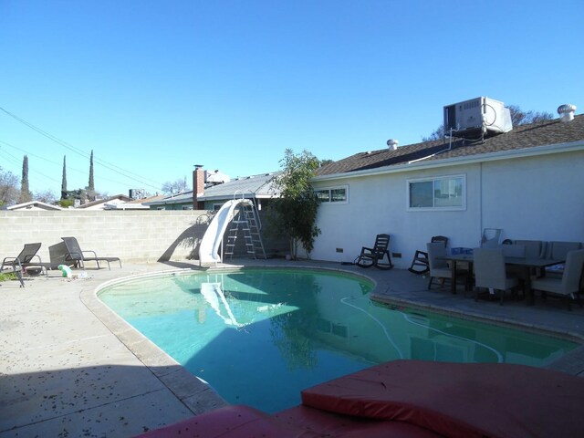 view of swimming pool with central AC unit, a patio area, and a water slide