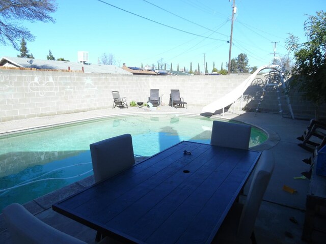 view of swimming pool with a water slide and a patio area