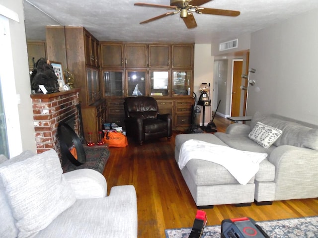 living room featuring ceiling fan, dark wood-type flooring, and a fireplace