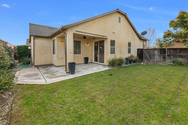 back of property with a patio, ceiling fan, and a lawn